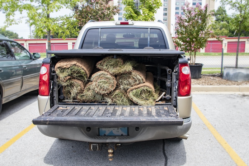 Close-up of back of pickup truck with bed protector and rolls of sod in the back with the tailgate down