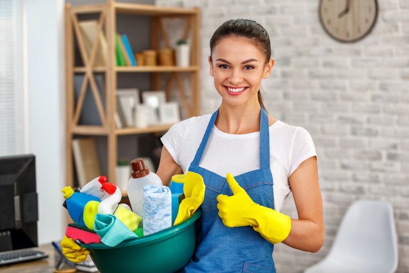 Cleaner in foreclosed home holding bucket of cleaning supplies.