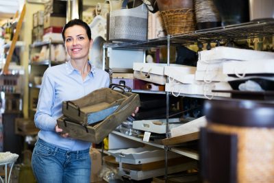 Smiling woman standing with wooden box demonstrating her home decor direct sales business.