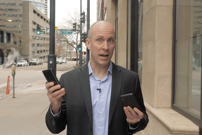 Dave Forest of Casey Research in the 5G Master Key presentation standing outside holding up two phones. One is a 4G-enabled phone and the other is a 5G-enabled phone.
